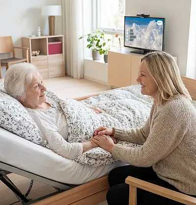 App-basierte Raumlösung NEDINA CONNECT im Pflegeheim Illustration eines Pflegezimmers: Eine Bewohnerin liegt im Bett, ihre Tochter sitzt auf einem Stuhl daneben. Auf einem Sideboard ist ein TV-Gerät mit digitaler Oberfläche zu sehen, das die app-basierte Raumlösung NEDINA CONNECT darstellt.