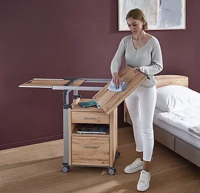 Nachttisch Aparto für Pflegeheimzimmer Nachttisch Aparto von Stiegelmeyer neben einem Pflegebett in einem Pflegeheimzimmer.