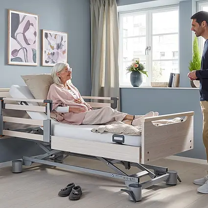 Libra care bed with Vario Safe in a resident’s room Libra care bed by Stiegelmeyer with Vario Safe safety sides in a bright, homelike, cosily furnished room.