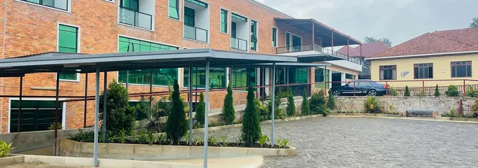 Ansicht der Solace Clinic in Kabuga Der Eingang der Solace-Klinik in der ruandischen Stadt Kabuga liegt an einem gepflasterten Platz. Das moderne Krankenhaus hat eine rote Klinkerfassade und grünes Fensterglas.