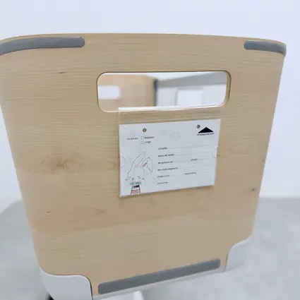 Detalle de una cuna Jovie de Stiegelmeyer con acabado en madera y soporte integrado para la placa identificativa del recién nacido.