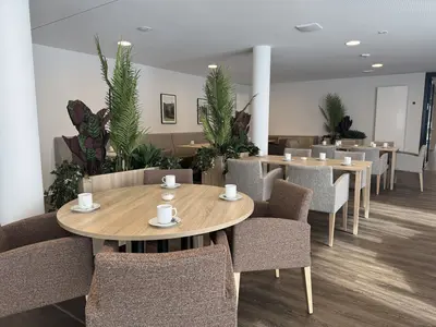Freundlich gestalteter Restaurantbereich mit Tischen, Sesseln und Pflanzen in einer compassio Seniorenresidenz