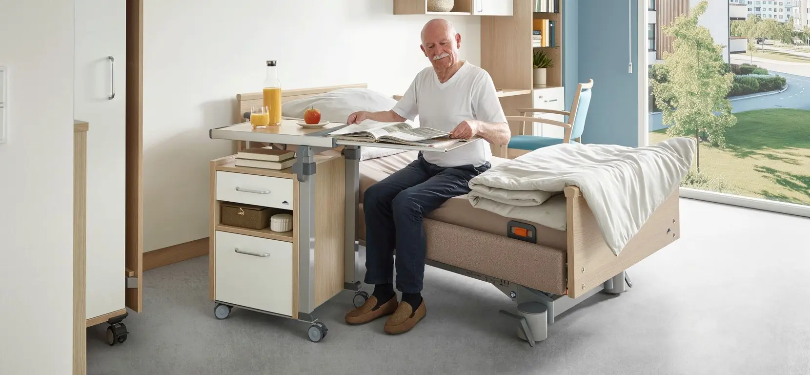 Moderna mesita de noche «Aparto» de Stiegelmeyer junto a una cama de cuidados en una habitación de hospital con un diseño acogedor.